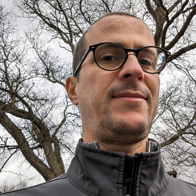 Selfie of Caluã, a white man wearing glasses and a black jacket.